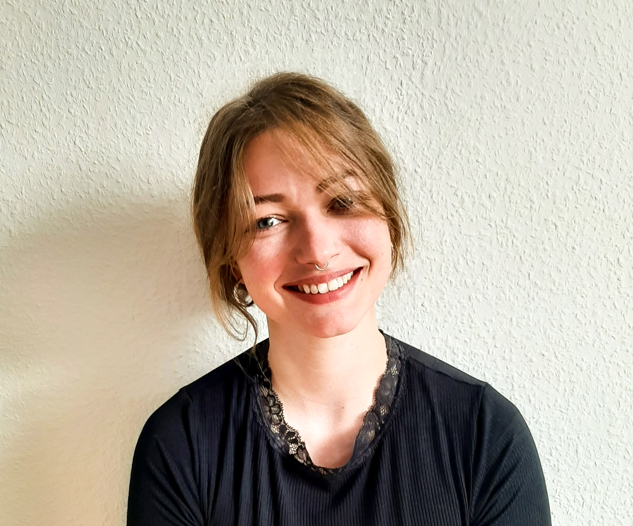 Rikke centreret i billedet, smilende direkte til kameraet med hovedet lidt på sned